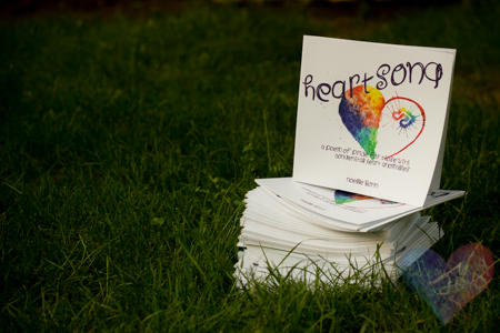 A stack of books titled "Heartsong: A poem of pride for those with Congenital Heart Anomalies"